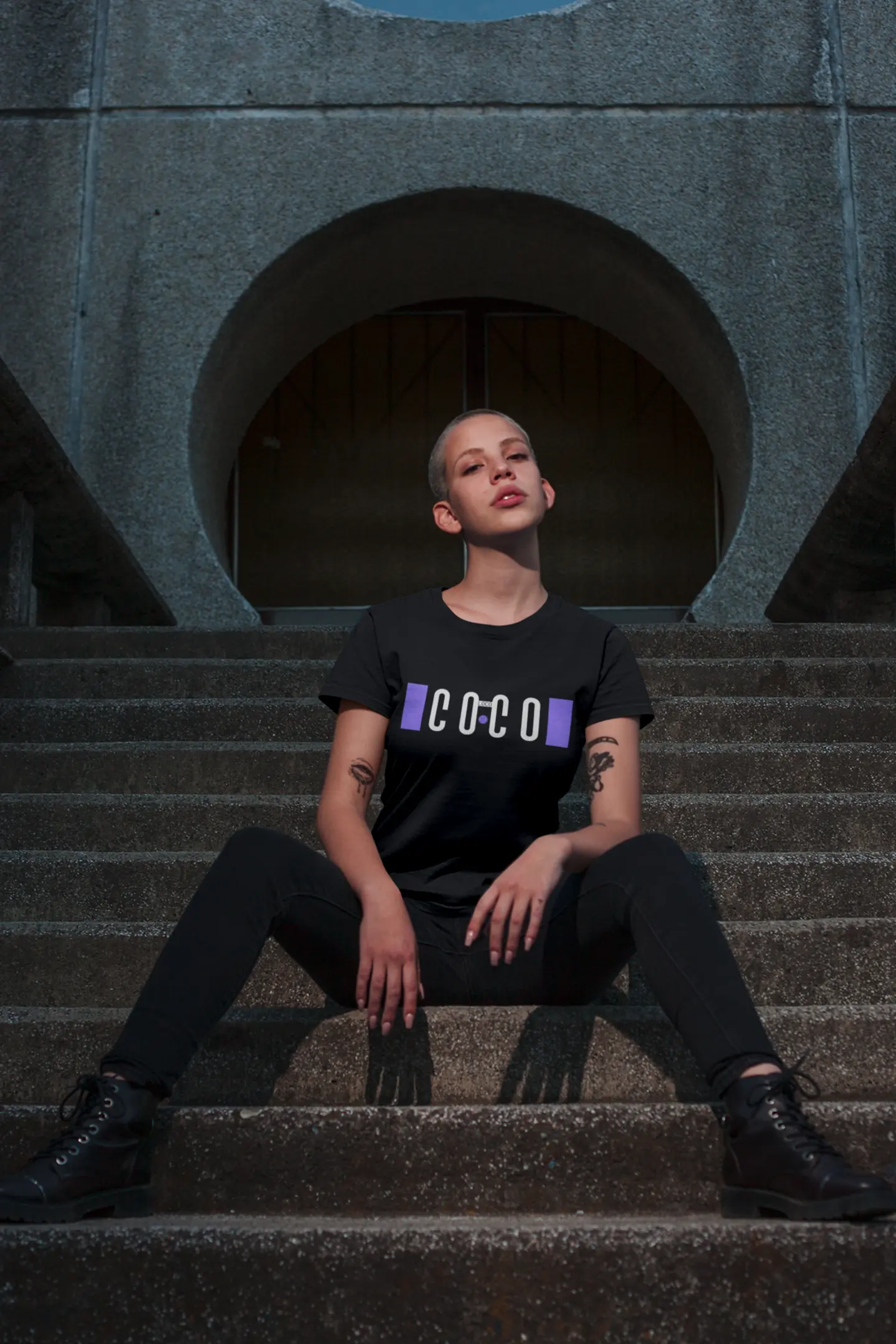 Model im schwarzen Coco-Loco-Shirt auf einer Treppe